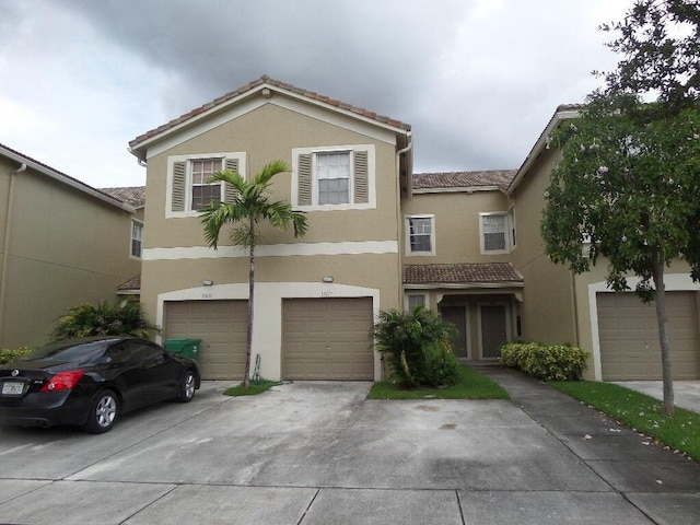 multi unit property featuring stucco siding, a tiled roof, concrete driveway, and an attached garage