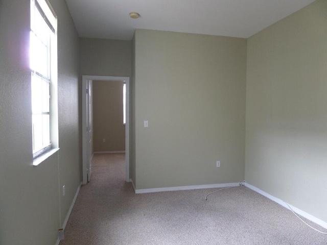 spare room with carpet floors, baseboards, and a smoke detector