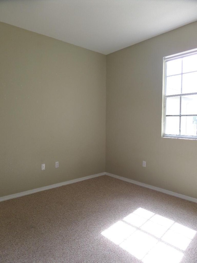 unfurnished room featuring carpet flooring and baseboards