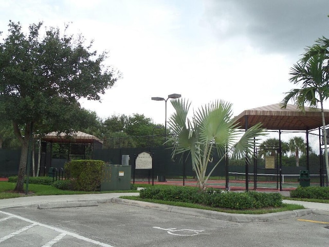 view of vehicle parking featuring a gazebo, a tennis court, and fence