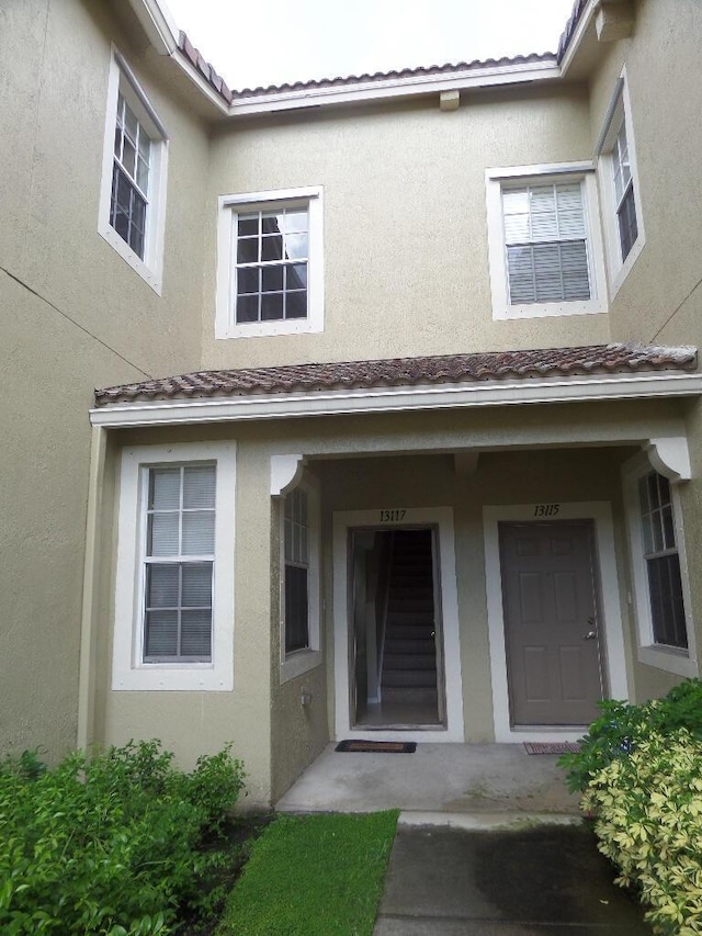view of exterior entry featuring stucco siding and a porch