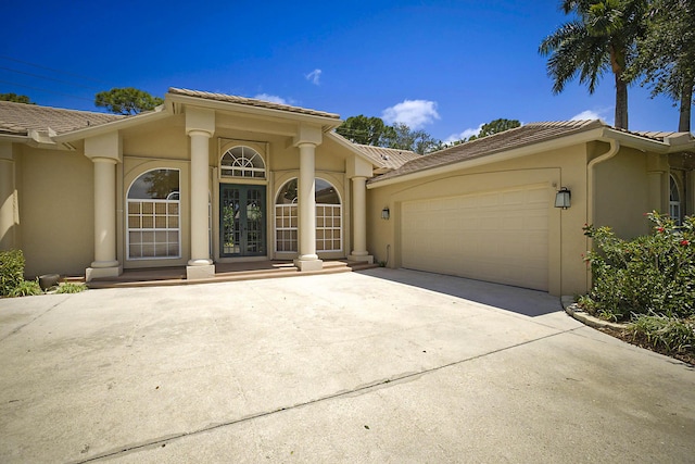 227 Shorewood Way, Jupiter, FL 33458 - view of exterior entry with a tiled roof, stucco siding, an attached garage, and concrete driveway
