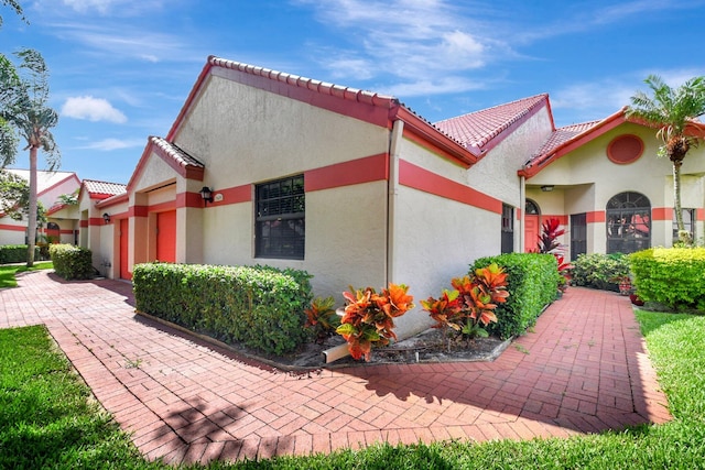 view of front of house with an attached garage, a tile roof, and stucco siding