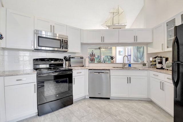 kitchen with black appliances, a sink, glass insert cabinets, and white cabinets