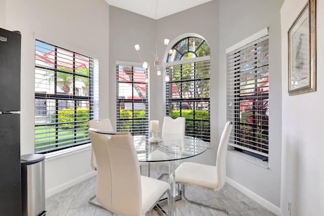 dining space with baseboards, light marble finish floors, and a chandelier