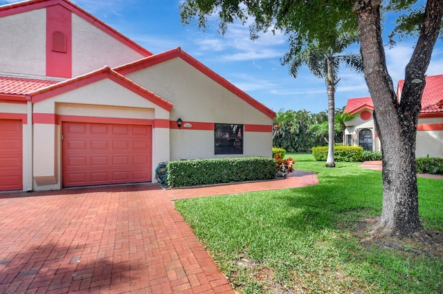 view of front of property with stucco siding, a front yard, an attached garage, decorative driveway, and a tiled roof