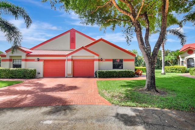 view of front facade with decorative driveway, stucco siding, an attached garage, a front lawn, and a tiled roof