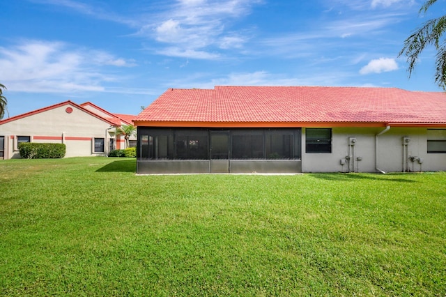 back of property with a sunroom, a yard, stucco siding, and a tile roof