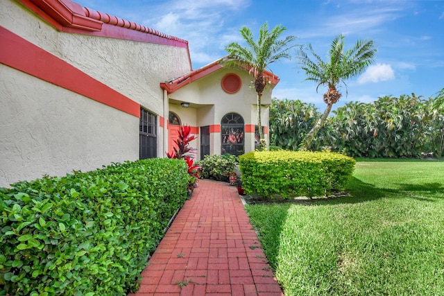 doorway to property featuring stucco siding and a lawn