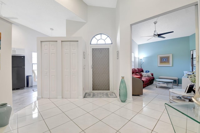 entryway featuring a ceiling fan, high vaulted ceiling, light tile patterned flooring, and baseboards