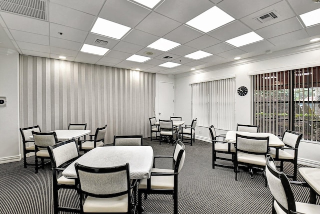 dining area featuring dark colored carpet, baseboards, and a drop ceiling