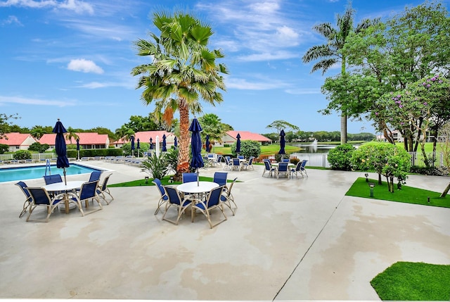 view of patio / terrace featuring a community pool, outdoor dining space, and a water view