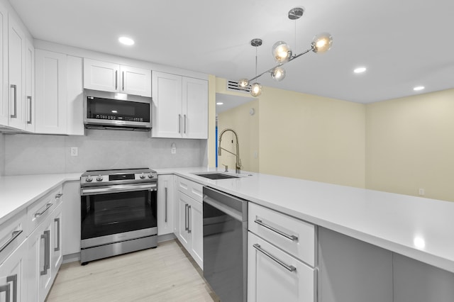 969 Normandy U, Delray Beach, FL 33484 - kitchen with stainless steel appliances, a sink, light wood-type flooring, white cabinets, and light countertops