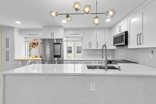 969 Normandy U, Delray Beach, FL 33484 - kitchen with stainless steel appliances, a sink, light countertops, white cabinets, and pendant lighting