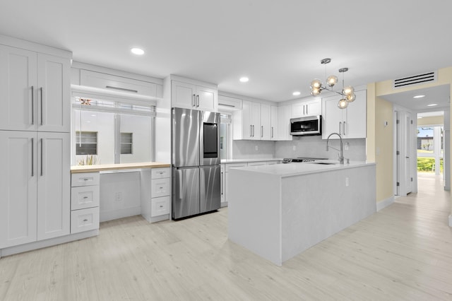 969 Normandy U, Delray Beach, FL 33484 - kitchen featuring stainless steel appliances, light wood finished floors, white cabinets, light countertops, and a peninsula