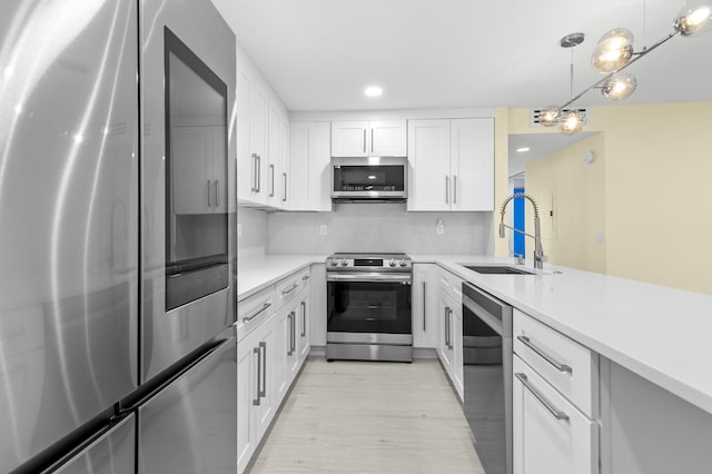 969 Normandy U, Delray Beach, FL 33484 - kitchen featuring appliances with stainless steel finishes, a sink, light wood-type flooring, light countertops, and white cabinets