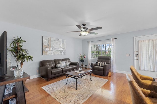 living room with ceiling fan, baseboards, and light wood-type flooring