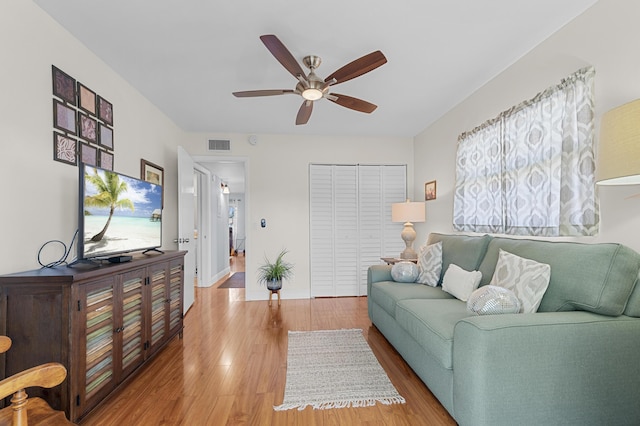 living area featuring a ceiling fan, wood finished floors, and baseboards