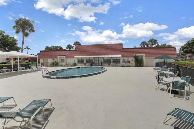community pool with fence and a patio area