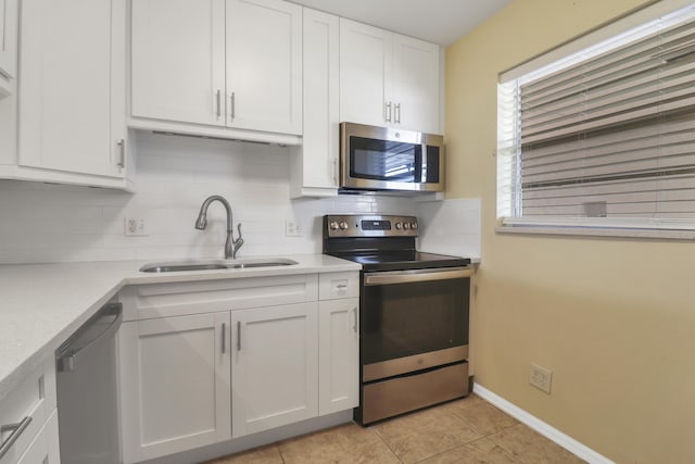 kitchen featuring stainless steel appliances, a sink, backsplash, white cabinets, and light countertops
