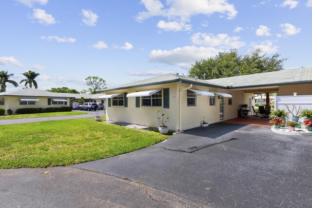 249 Cardinal Ln, Delray Beach, FL 33445 - view of front of home with a front yard, driveway, an attached carport, and stucco siding