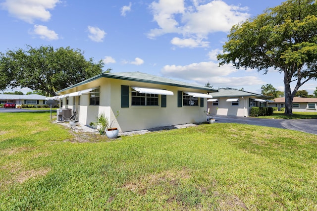 249 Cardinal Ln, Delray Beach, FL 33445 - view of front of property featuring central AC unit, stucco siding, a front yard, and driveway