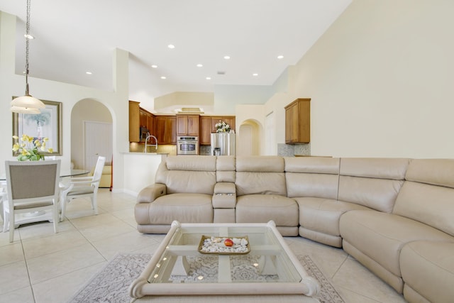 living area with light tile patterned floors, arched walkways, a towering ceiling, and recessed lighting