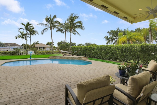view of swimming pool with a ceiling fan, a patio area, and a fenced backyard