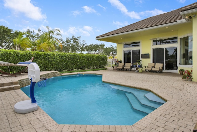view of swimming pool featuring a patio area, ceiling fan, and fence