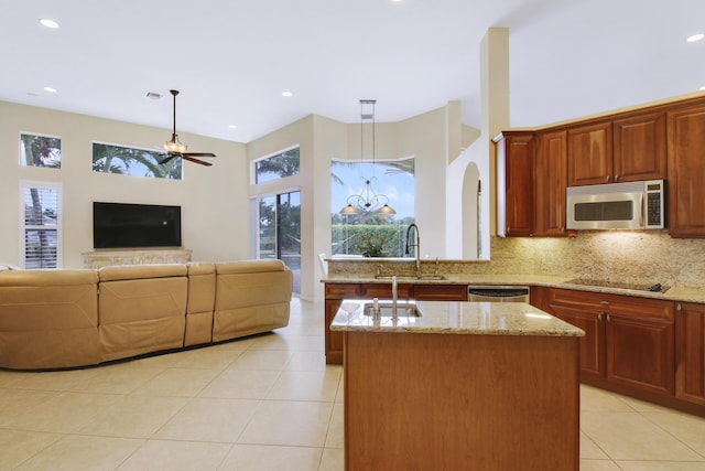 kitchen with stainless steel appliances, a high ceiling, a sink, open floor plan, and backsplash