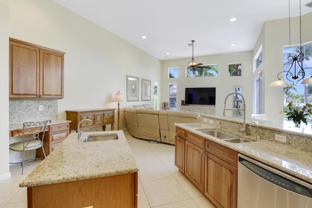 kitchen featuring stainless steel dishwasher, a sink, ceiling fan, light tile patterned flooring, and a high ceiling