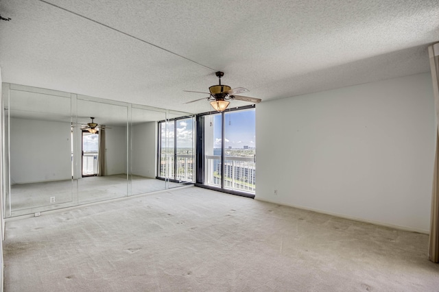 123 Lakeshore Dr Unit 1644, North Palm Beach, FL 33408 - spare room featuring a wall of windows, ceiling fan, a textured ceiling, and carpet flooring