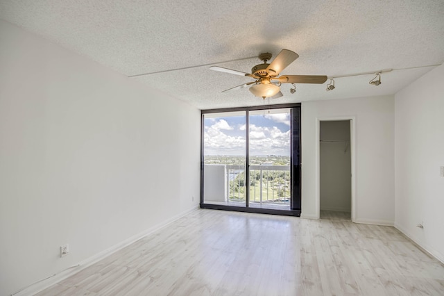 123 Lakeshore Dr Unit 1644, North Palm Beach, FL 33408 - empty room featuring expansive windows, a textured ceiling, light wood-style flooring, a ceiling fan, and baseboards