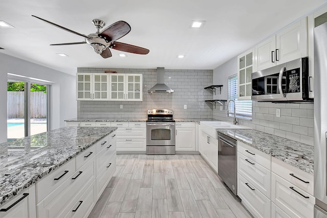 kitchen with appliances with stainless steel finishes, wall chimney exhaust hood, plenty of natural light, ceiling fan, and recessed lighting