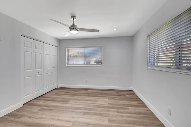 unfurnished bedroom featuring multiple windows, light wood finished floors, and baseboards