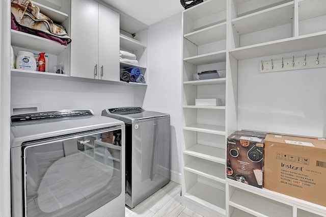 laundry room with washing machine and clothes dryer, cabinet space, and baseboards