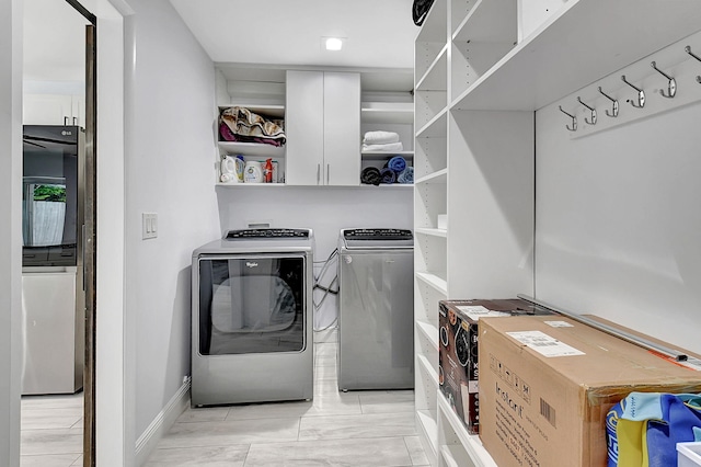 clothes washing area featuring independent washer and dryer and baseboards