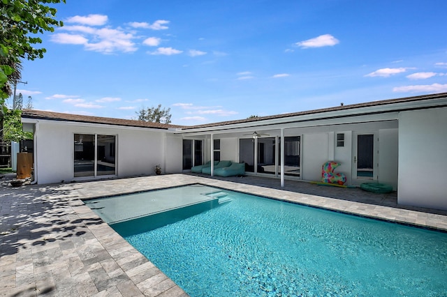 rear view of house featuring a patio area, stucco siding, an outdoor pool, and ceiling fan