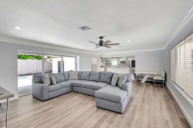 living room with light wood-type flooring, ornamental molding, a ceiling fan, baseboards, and recessed lighting