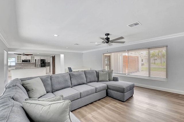 living room with crown molding, a ceiling fan, light wood-type flooring, baseboards, and recessed lighting