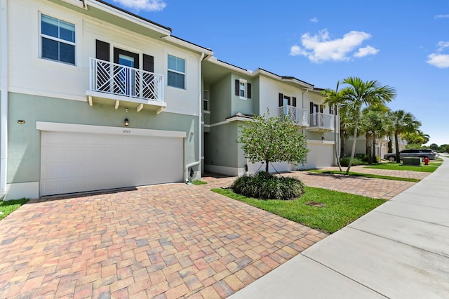 townhome / multi-family property with decorative driveway, stucco siding, an attached garage, and a balcony