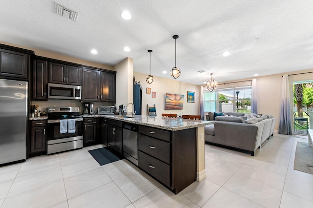kitchen with appliances with stainless steel finishes, light stone countertops, a peninsula, a chandelier, and recessed lighting