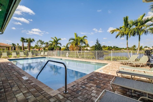 community pool featuring a patio, fence, and a water view