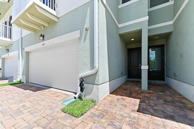 doorway to property featuring stucco siding and an attached garage