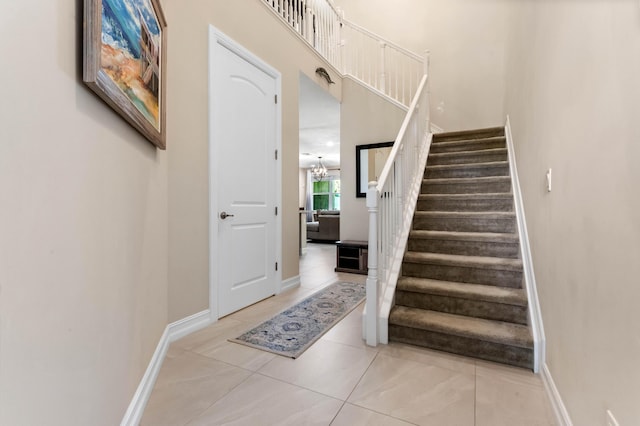 staircase featuring tile patterned floors, baseboards, and a chandelier