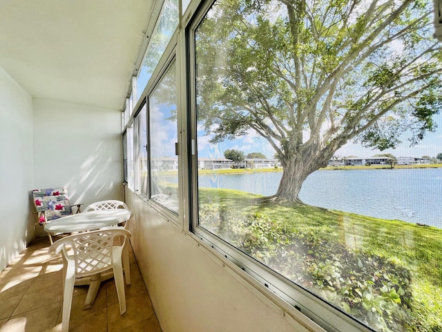 sunroom featuring tile patterned floors and a water view