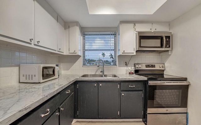 kitchen featuring appliances with stainless steel finishes, a sink, white cabinets, and light countertops