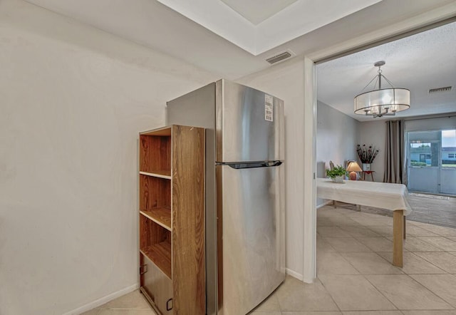 kitchen with freestanding refrigerator, a chandelier, baseboards, and light tile patterned flooring