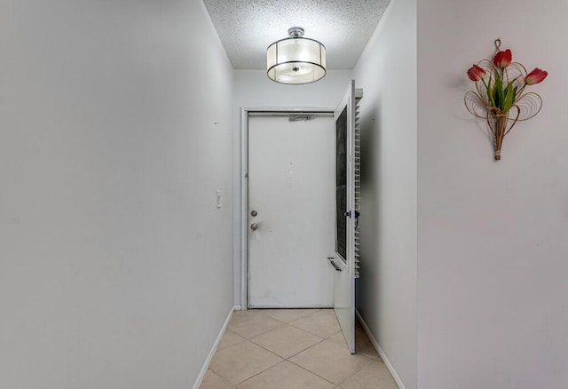 doorway to outside with light tile patterned flooring, baseboards, and a textured ceiling