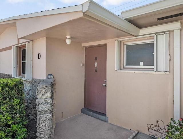 doorway to property featuring stucco siding